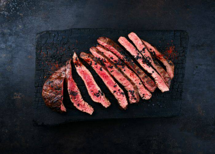 Sliced, medium-rare wagyu beef on a slab of charcoal.